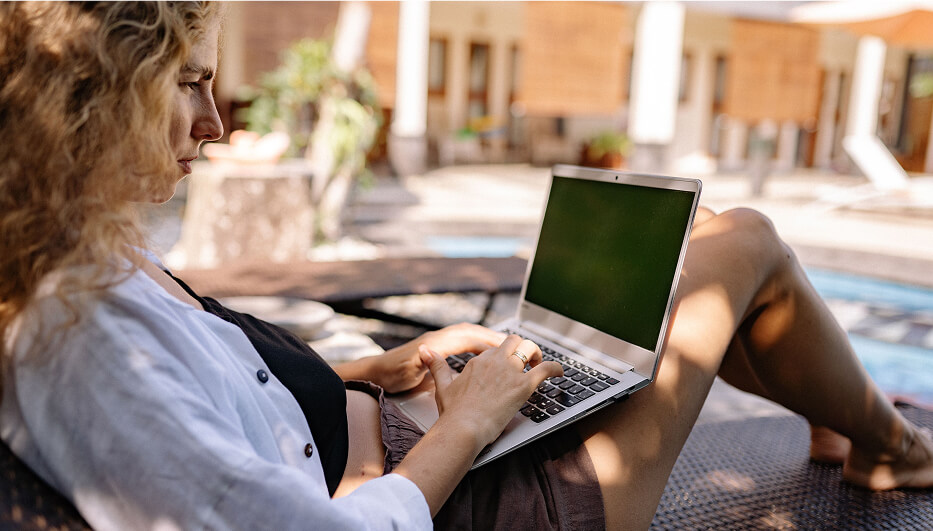 woman sitting by pool with laptop