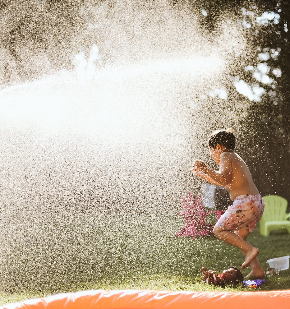 child playing in sprinkler